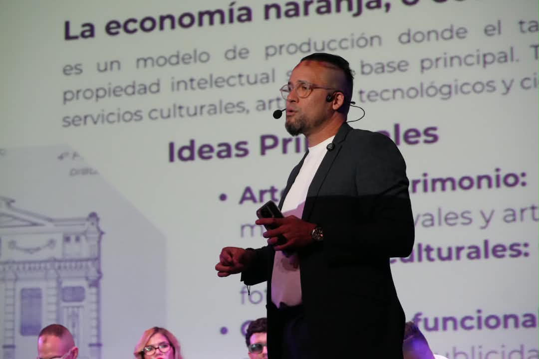 Abg. Daniel Centeno dando una conferencia con micrófono de diadema frente a una pantalla